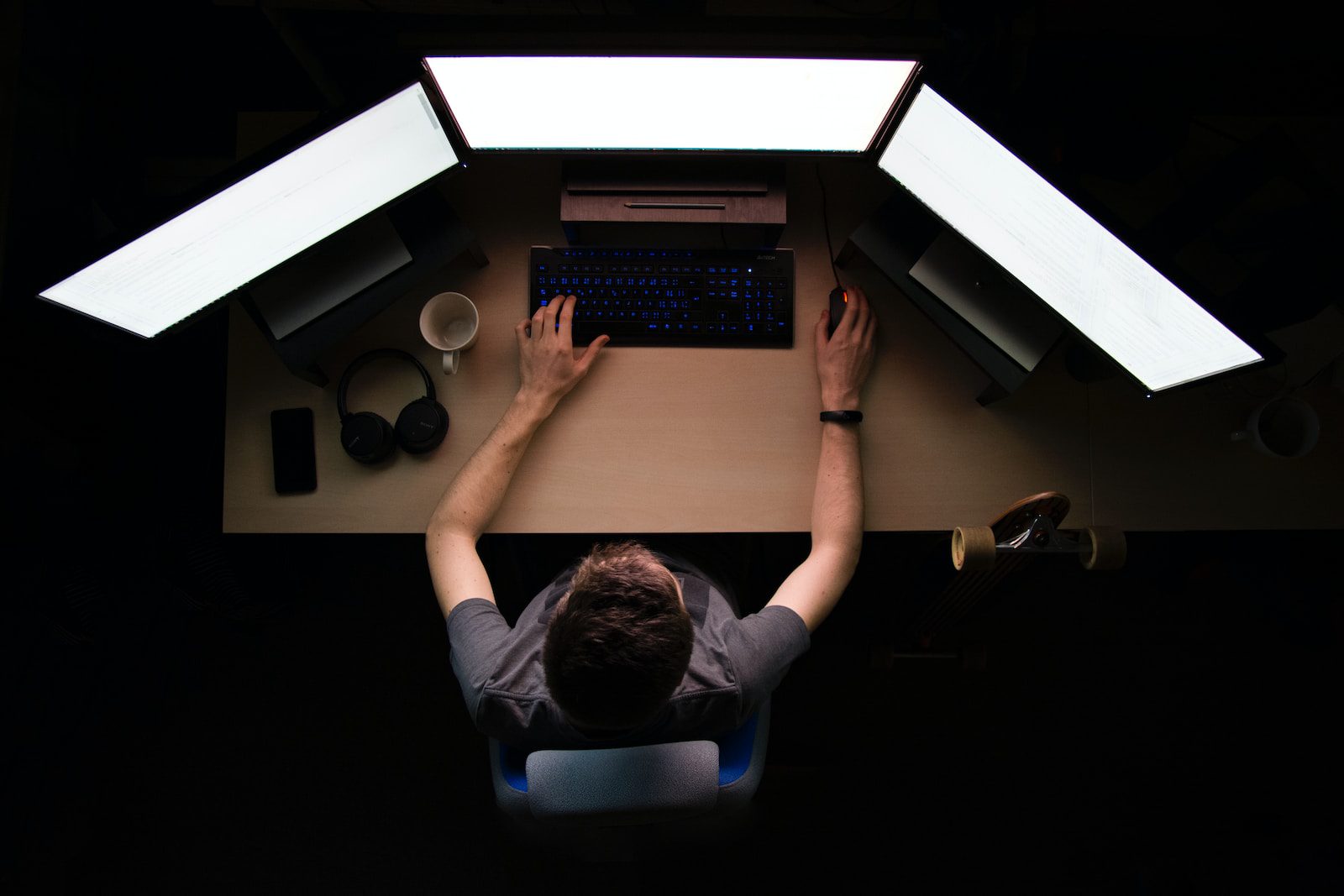 man facing three computer monitors while sitting
